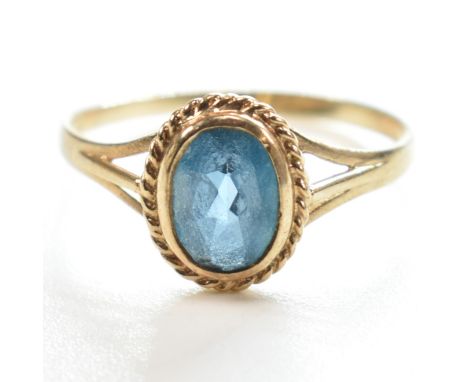 A hallmarked 9ct gold and topaz single stone ring. The ring having a single bezel set oval cut topaz in a rope twist decorati
