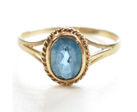 A hallmarked 9ct gold and topaz single stone ring. The ring having a single bezel set oval cut topaz in a rope twist decorati