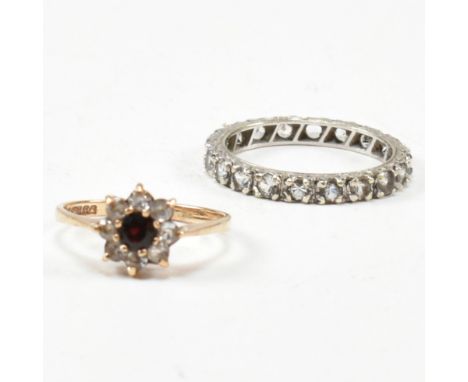 Two 9ct gold and gem set rings. The rings to include a gem set white gold eternity ring stamped 9ct. A garnet and white stone