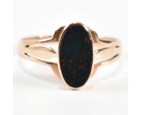 A gold and bloodstone ring. The ring set with a bezel set oval cut bloodstone to pierced shoulders. Hallmarked rubbed. Surfac