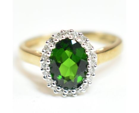 A hallmarked 9ct gold, tourmaline and diamond cluster ring. The ring set with a central oval cut tourmaline surrounded by a h