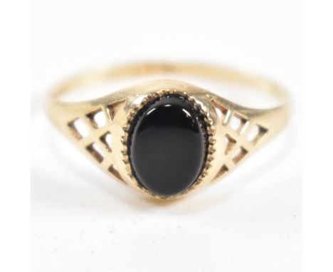 A hallmarked 9ct gold and black stone signet ring. The ring set with a bezel set oval cut black stone with millegrain border 