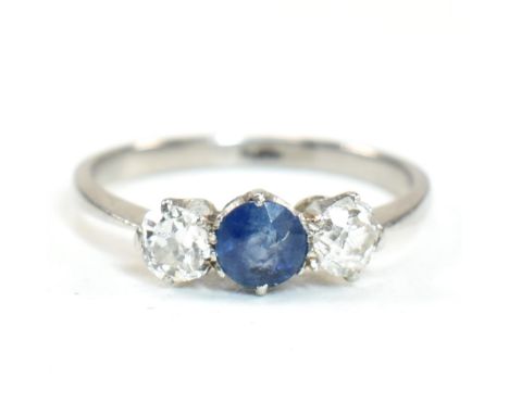 A platinum, sapphire and diamond three stone ring. The platinum trilogy ring having a central round cut sapphire flanked by t