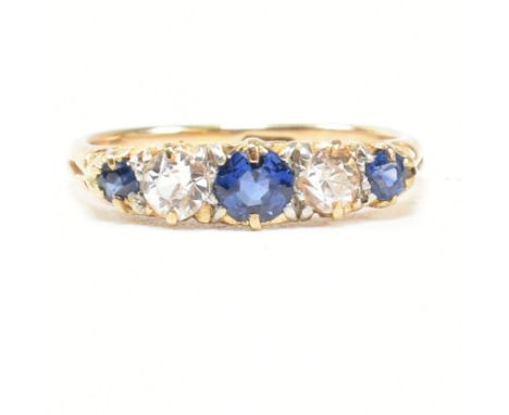 An 18ct gold and sapphire five stone gypsy ring. The ring set with blue and white sapphire to a scrolled mount. Weight 3.1g. 