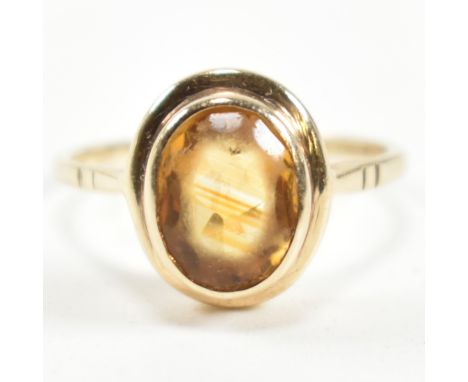 A hallmarked 9ct gold and citrine ring. The ring having a bezel set oval cut citrine in a 9ct gold oval mount to notched shou