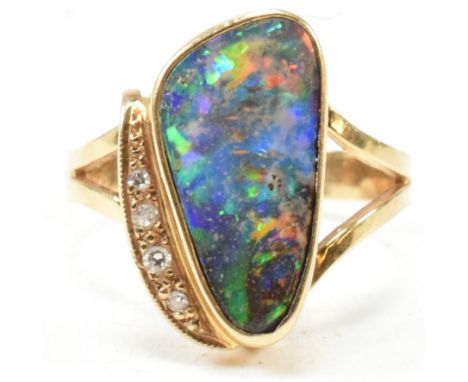 An 18ct gold opal and diamond ring. The ring set with an opal doublet having four single cut diamond accents to bifurcated sh