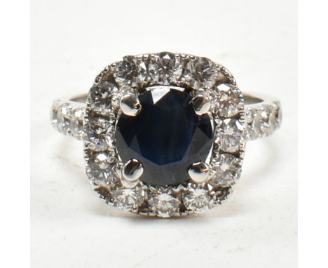 A 14ct white gold, sapphire and diamond halo ring. The ring set with a central round mixed cut sapphire framed by a halo of r