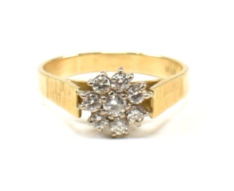 An 18ct gold and diamond cluster ring. The ring set with eight round brilliant cut diamonds with bark effect shoulders to pla