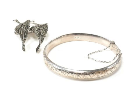 A hallmarked silver hinged bangle together with a hallmarked marcasite brooch pin. The lot to include a hallmarked silver eng