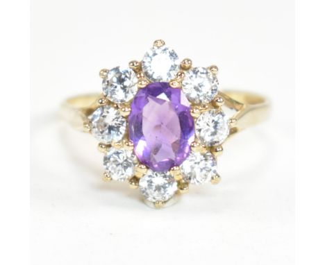 A hallmarked 9ct gold, amethyst and white stone cluster ring. The ring having a central oval cut amethyst surrounded by a hal