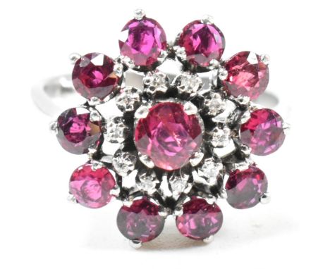 A white gold ruby and diamond cluster ring. The ring set with round cut rubies and single cut diamonds to tapering shank. Unm