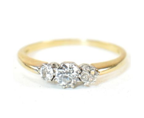 An 18ct gold and diamond three stone ring. The ring having a central round brilliant cut diamond flanked by two smaller round