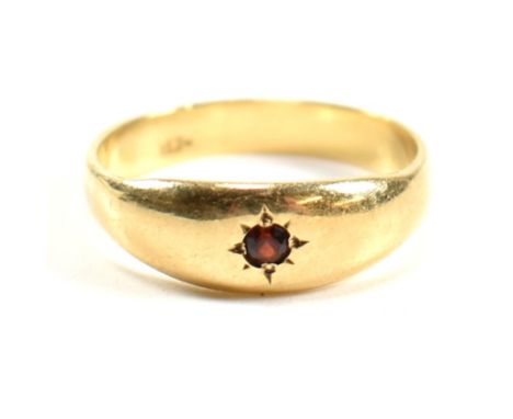 An 18ct gold and garnet gypsy ring. The ring having a central round cut star set garnet in a domed mount to tapered shoulders