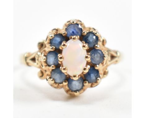 A hallmarked 9ct gold, sapphire and opal cluster ring. The ring set with a central oval opal cabochon surrounded by a halo of