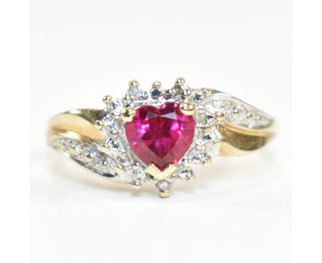 A hallmarked 9ct gold, diamond and ruby cluster ring. The ring having a central heart cut ruby set in a mount set with three 