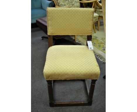 An early 18th century oak side chair the rectangular padded back above a stuff over seat, raised on ring turned front support