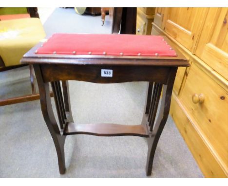 A red upholstered lyre stool.