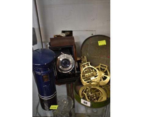 Eight early horse brasses contained in a Dainty Dinah figural horseshoe toffee tin together with a moneybox & vintage camera.