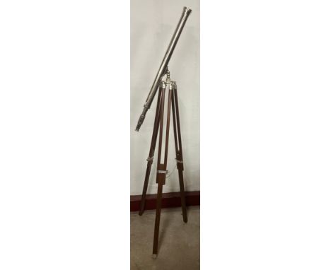 A large chrome telescope and wooden tripod with adjustable legs 