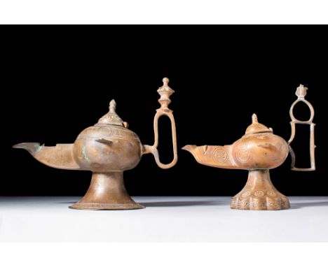 Ca. AD 1100 - 1300.
A pair of Khorasan oil lamps, both with rounded finials atop tall handles, atop a flared base, one decora