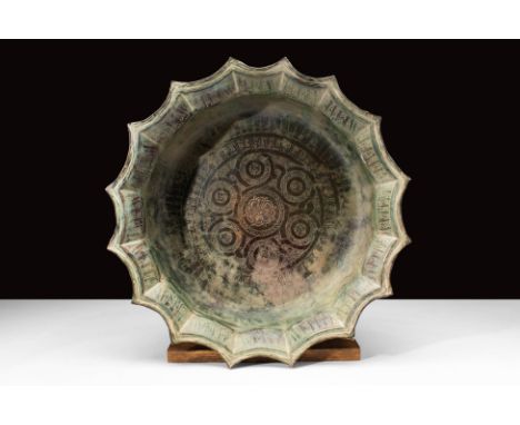 Ca. 1100-1300 AD. A brass basin with a distinctive scalloped edge and intricately engraved interior. This basin features a fl