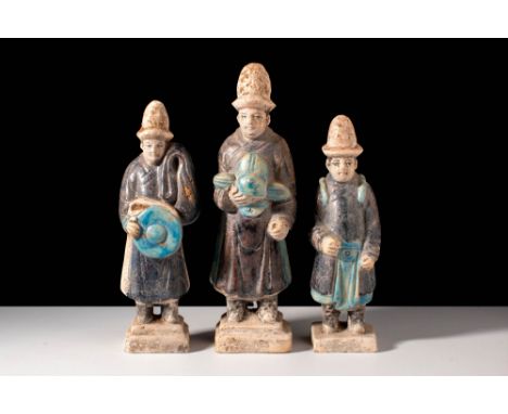 Ming Dynasty, Ca. AD 1368-1644.A group of three terracotta figures. They appear to be attendants, dressed in aubergine-glazed