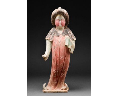 Tang Dynasty, Ca. AD 618-907.
A terracotta court lady, depicted standing upright, wearing a long red dress with a flowing bla