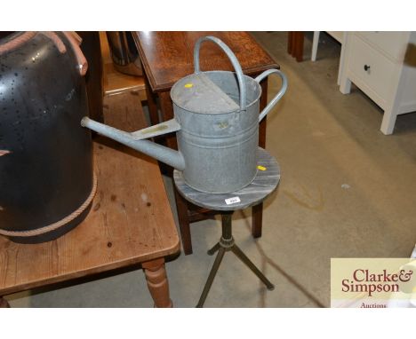 A two gallon galvanised watering can and an onyx topped tripod garden table