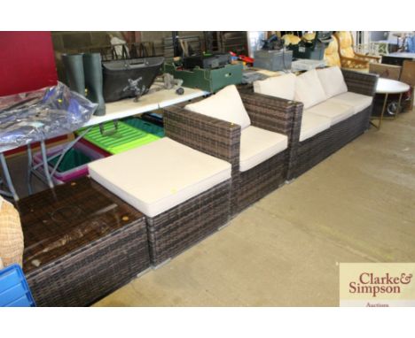 A rattan style garden furniture set comprising three seater settee, chair, glass top table and stool