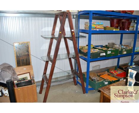 A wooden free standing ladder shelf unit with three glass shelves