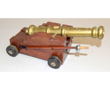 An impressive desk top model of an 18th century ships cannon with a brass barrel of 25cms length seated on a wooden carriage.