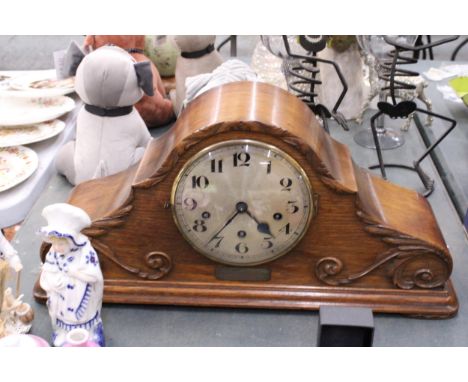 A LARGE OAK CASED MANTLE CLOCK WITH CARVING TO THE FRONT, PENDULUM AND KEY - HAS AN INSCRIPTION PLAQUE DATING IT TO 1925, HEI