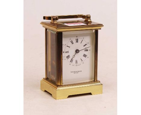 A 20th century lacquered brass cased carriage clock, having an enamelled dial with inner Roman numerals and outer Arabic nume