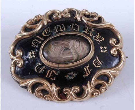A mid Victorian yellow metal and black enamel mourning brooch set with a plait of hair under crystal annotated to the obverse