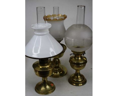An early 20th century brass pedestal oil lamp, having opalescent glass shade; together with two other lacquered brass oil lam