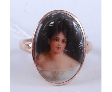 A continental yellow metal and enamel porcelain set ring, the oval porcelain panel painted with a bust portrait of a young wo