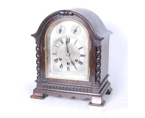 An early 20th century oak cased mantel clock, the silvered dial showing Roman numerals with slow/fast and chime/silent, the e