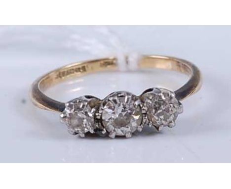 An early 20th century 18ct gold diamond three stone ring, the claw set round cuts in a line setting, total diamond weight est