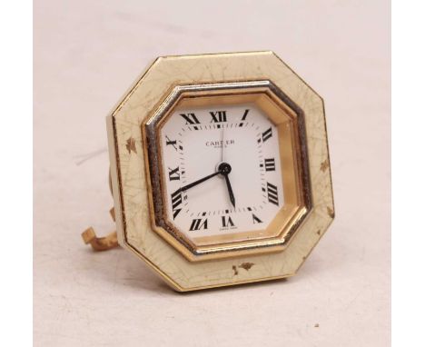 A Cartier travel alarm clock, having an octagonal dial with Roman numerals and signed Cartier Paris, within a cream and gilt 