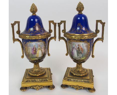 A pair of ormolu mounted Sevres style two-handled garniture urns the cobalt blue body with painted panels of courting couples