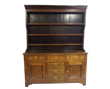 A 19th Century oak dresser the three tier plate rack with overhanging cornice above a row of three drawers above two cupboard