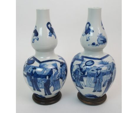 A pair of Chinese blue and white double gourd vases painted with mandarins and courtiers in fenced gardens beneath children p