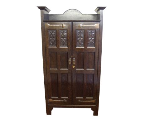 A Scottish Arts and Crafts stained oak hall cupboard by Shapland and Petter, Barnstaple with a pair of carved panelled doors 