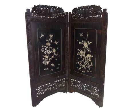 A Japanese two-fold ebonised draught screen applied in relief with birds and foliage, in mother of pearl within a carved surr