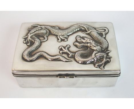 A Chinese silver cigarette box and cover embossed with a dragon enclosing two wood lined divisions, stamped LH Co., 13cm wide