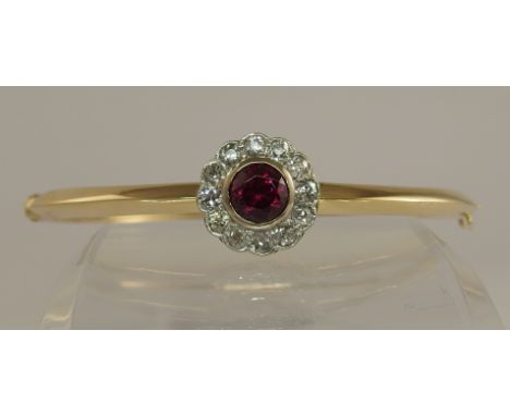 A ruby and diamond bangle set in yellow and white metal, the central ruby exhibits silk inclusions, surrounded with a circlet