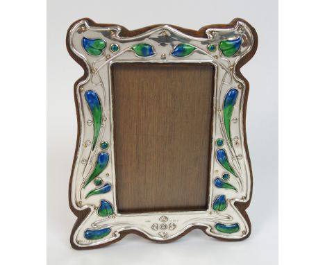 An Art Nouveau silver photo frame by Henry Williamson Limited, Buckingham 1905, of shaped rectangular form with stylised foli