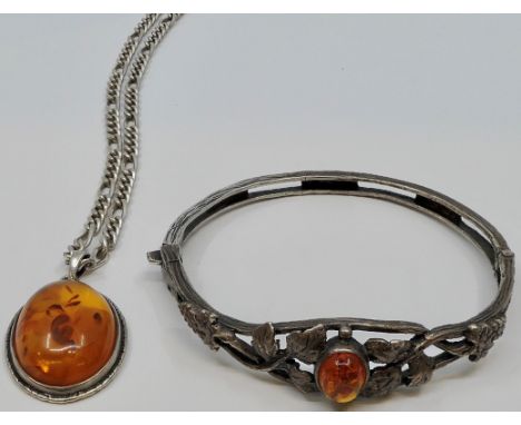 An oval amber pendant in white metal setting stamped SILVER, on hallmarked silver neck chain; and a white metal bangle moulde