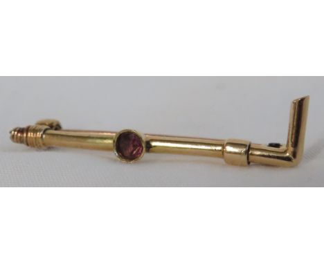 A yellow metal brooch modelled as a hunting crop and set centrally with a small amethyst, length 37mm, gross weight 2.2g