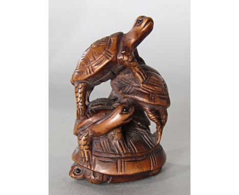 A carved hard wood netsuke in the form of four clambering tortoise 